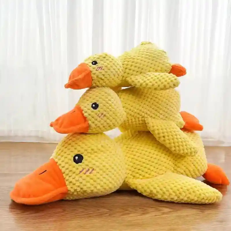 Brinquedo de pato amarelo de pelúcia antiestresse para cachorro empilhado em três tamanhos, sobre piso de madeira.