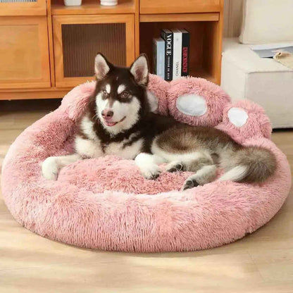 Cachorro deitado em cama redonda rosa com formato de pata de urso em sala de estar